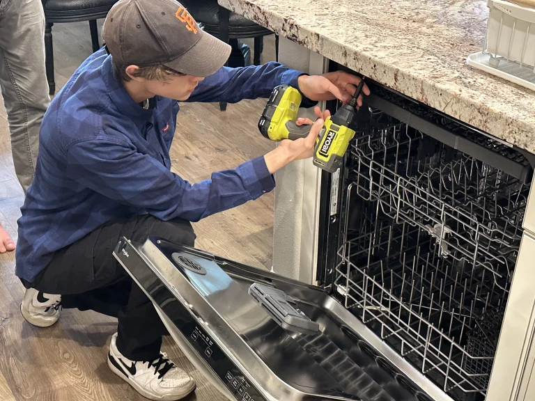 an appliance repair technician in Fresno, CA is repairing a broken dishwasher